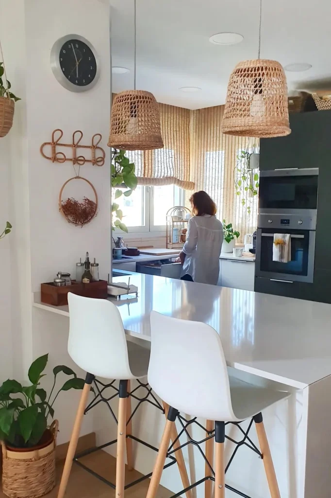 Cozinha Boho Escandinavo com luminárias de fibras, bancadas brancas e plantas pendentes.