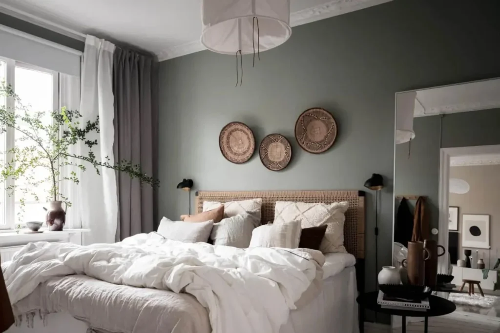 Quarto Boho Escandinavo com parede verde suave, cabeceira de fibras naturais e roupas de cama neutras.