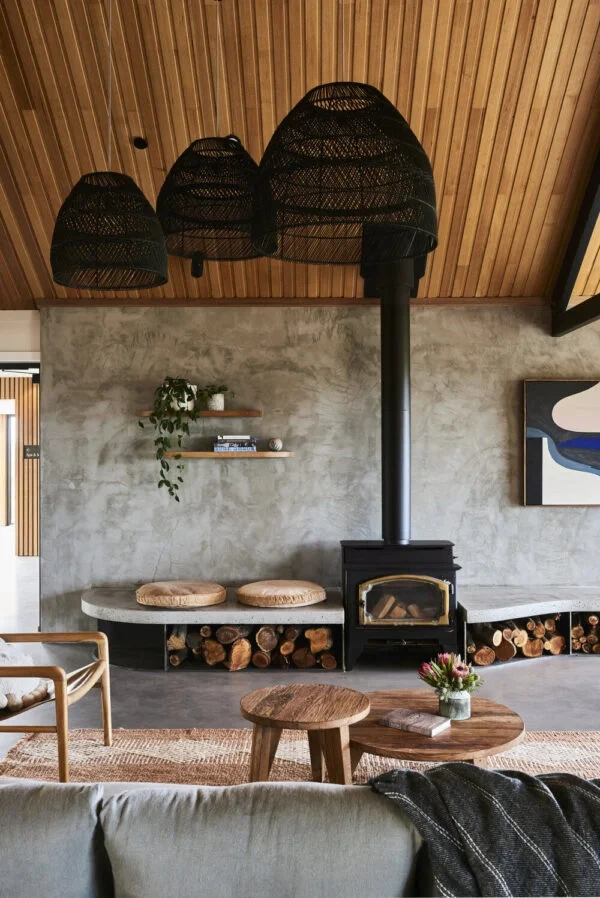Sala Boho Escandinavo com teto de madeira, lareira preta moderna, mesa de centro e bancos com assentos de palha.