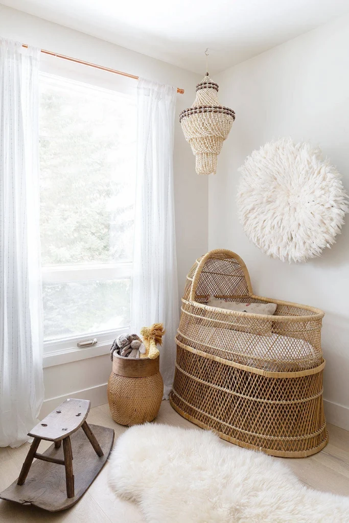 Quarto de bebê Boho Escandinavo com berço de vime, luminária de fibras e tapete felpudo branco.