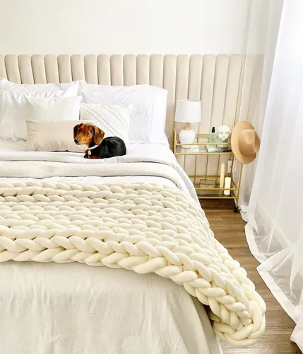 Manta maxi tricot em algodão cru sobre cama branca decorada com travesseiros