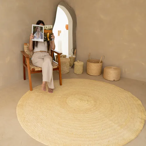 Tapete redondo de fibra natural em tom cru decorando ambiente boho minimalista