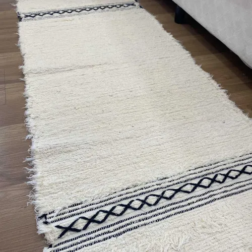Tapete Boho retangular em algodão cru com franjas e detalhes geométricos em preto, usado para trazer aconchego à cozinha.