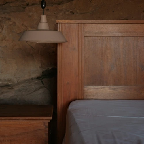 quarto de casal e casa de campo moderna com cama em madeira rústica, roupa de cama em linho cinza e parede de pedra